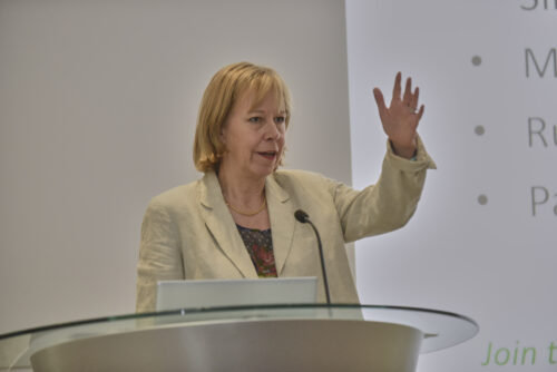 A woman waving as she speaks at a lectern at the 2019 Parliamentary Bike Ride