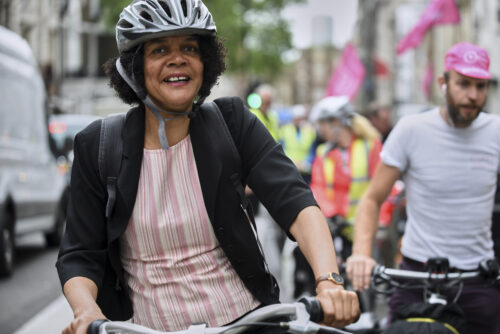 A smiling woman in a cycle helmet riding with others on the 2019 Parliamentary Bike Ride