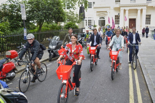 A group of riders on hire bikes and their own bikes heading down a Westminster street on the 2019 Parliamentary Bike Ride