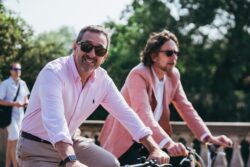 Two smiling men in sunglasses cycling side by side on the 2023 Parliamentary Bike Ride