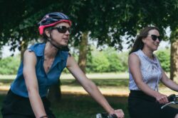 Two women in sunglasses cycling through a park on the 2023 Parliamentary Bike Ride