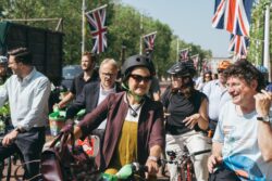 Smiling riders waiting on The Mall under Union flags at the 2023 Parliamentary Bike Ride