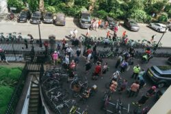 View from above of riders and bikes gathered in a street below railings at the 2023 Parliamentary Bike Ride