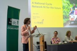 A man speaking at a lectern in front of a Sustrans slide titled A National Cycle Network fit for the future
